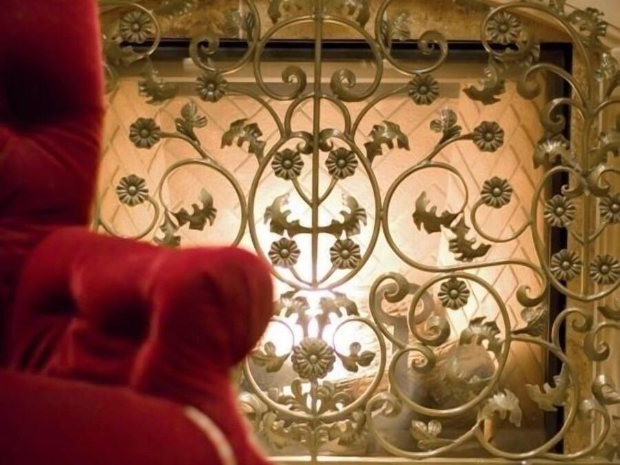 Una habitación con una celosía metálica decorativa y un sillón rojo tapizado.