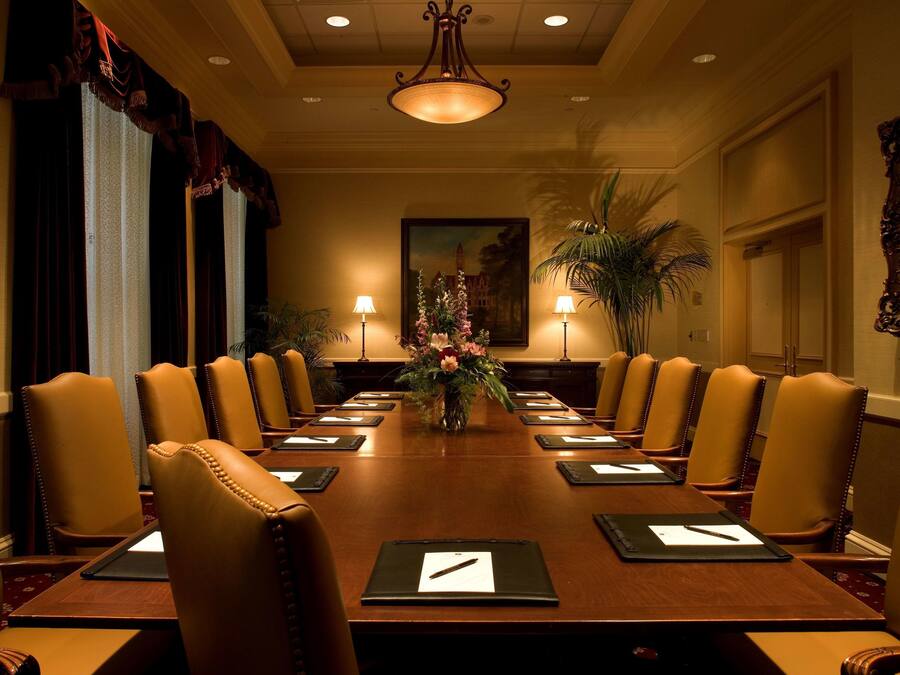A conference room with a long table, multiple chairs, and a vase of flowers.