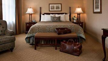 A hotel room with a large bed, two bedside tables, a bench, and a chair.
