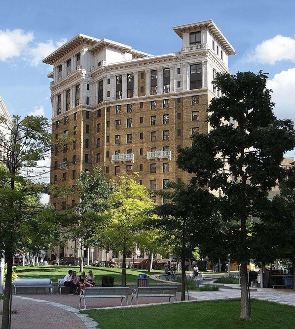 A multi-story building with a classical architectural style, featuring a central courtyard with benches and trees.