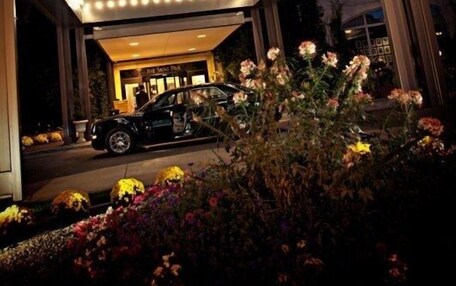 A hotel entrance with a canopy, a car parked in front, and a building in the background.