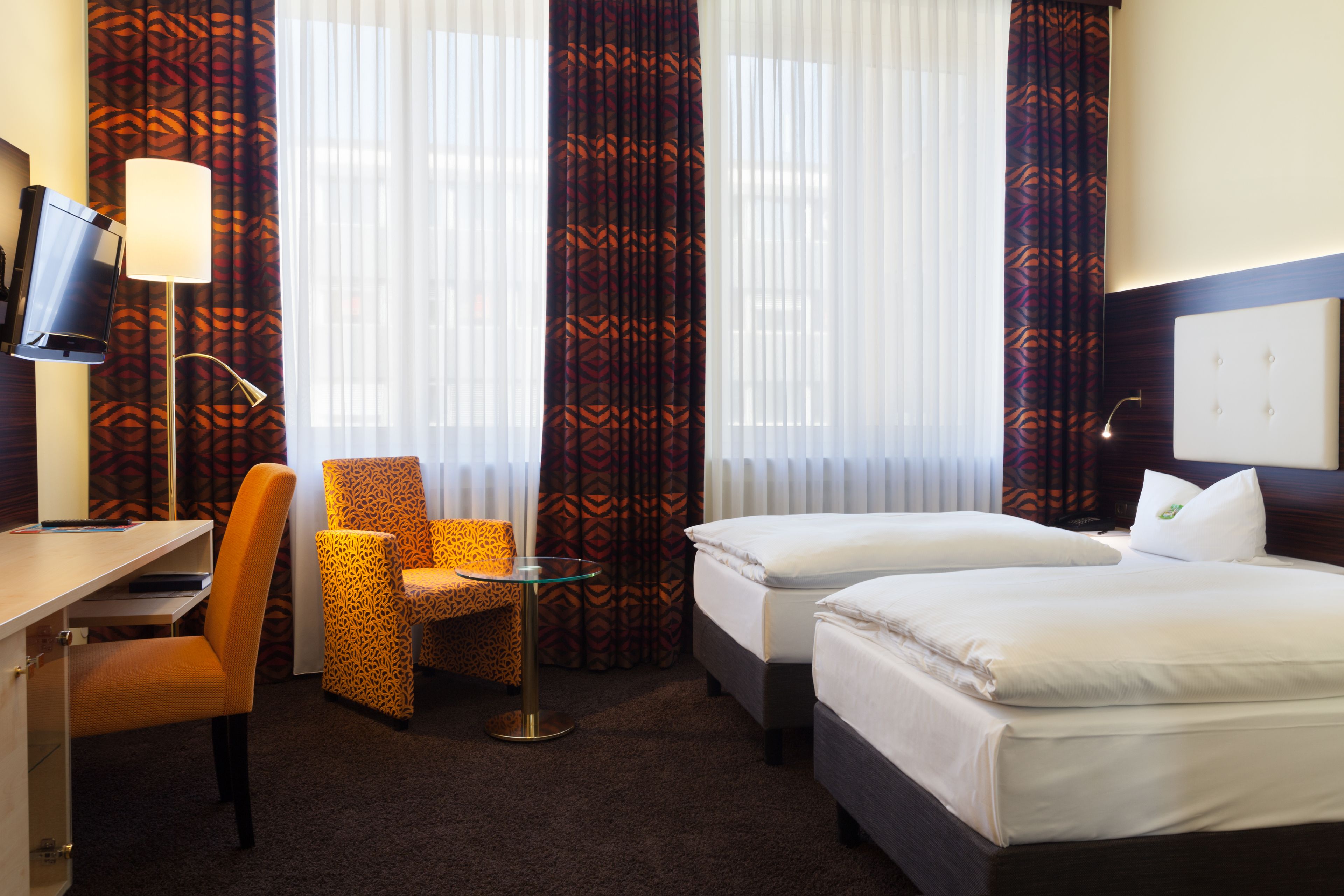 Una habitación de hotel con dos camas, un escritorio, una silla y un televisor.