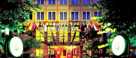 A hotel entrance with a sign reading "HOTEL AUGUSTA" and multiple flags.
