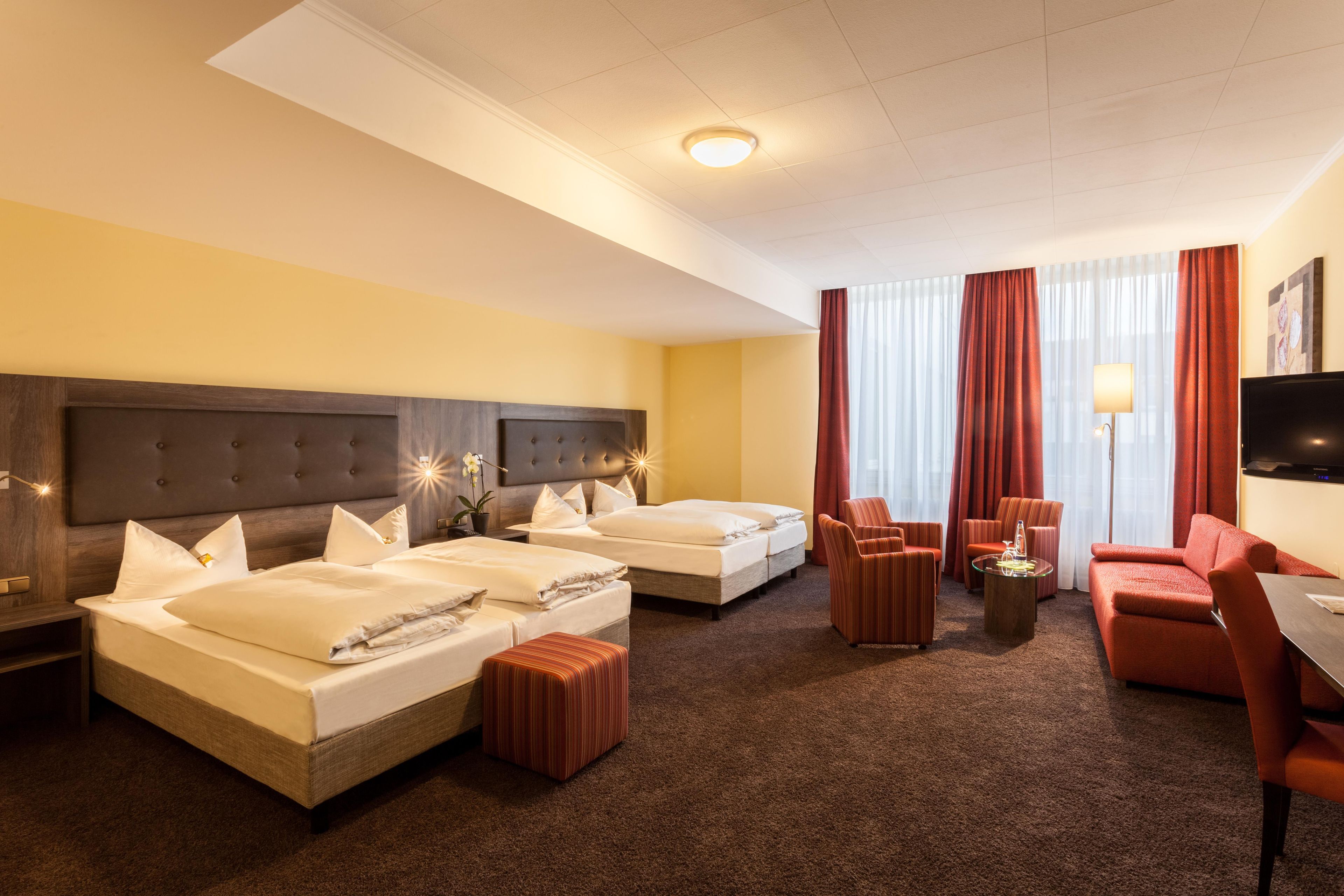 Habitación de hotel con dos camas, un sofá, un televisor y una mesita.