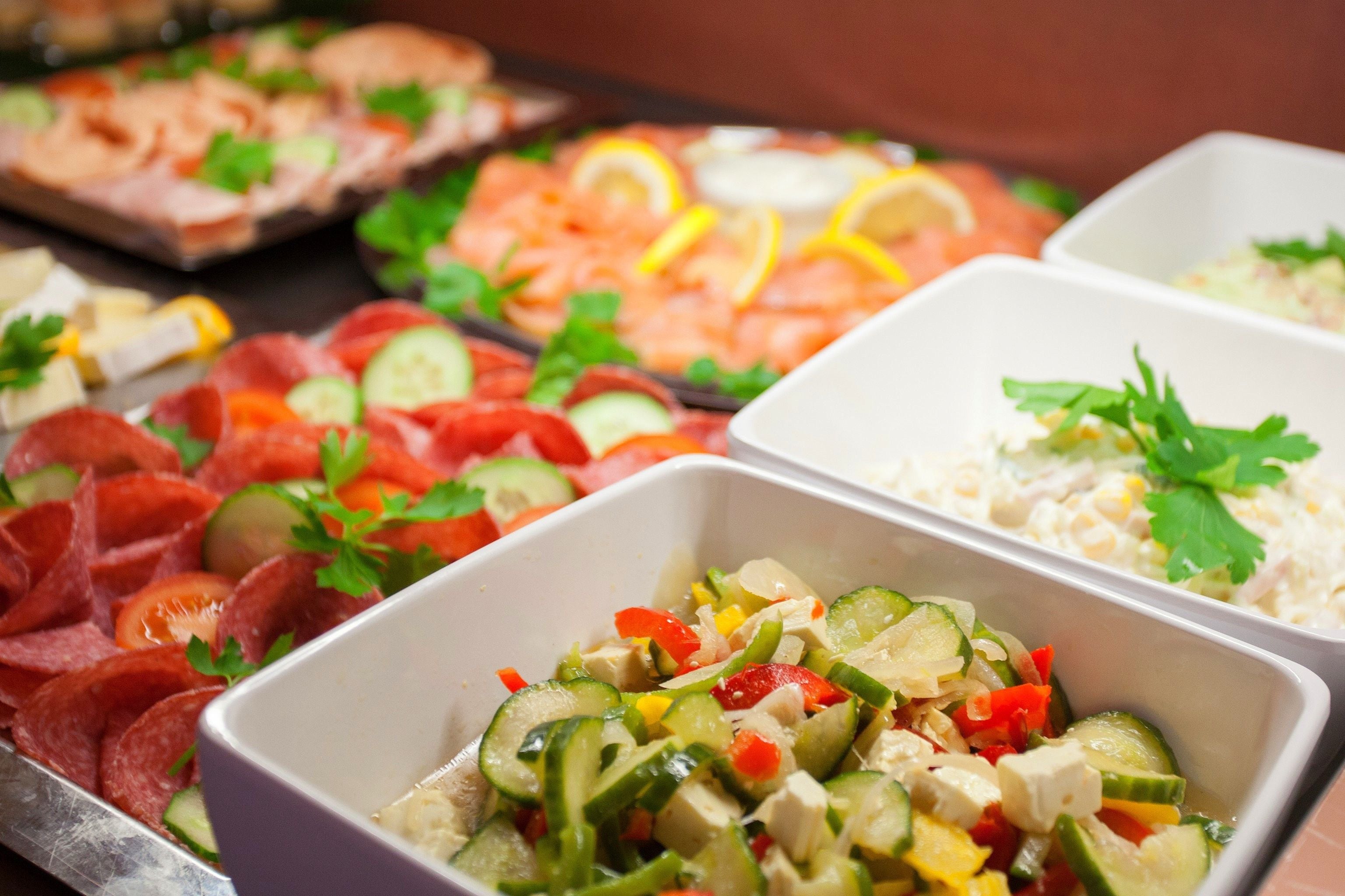 Ein Buffet mit verschiedenen Speisen, darunter Aufschnitt, Gemüse und Salate.