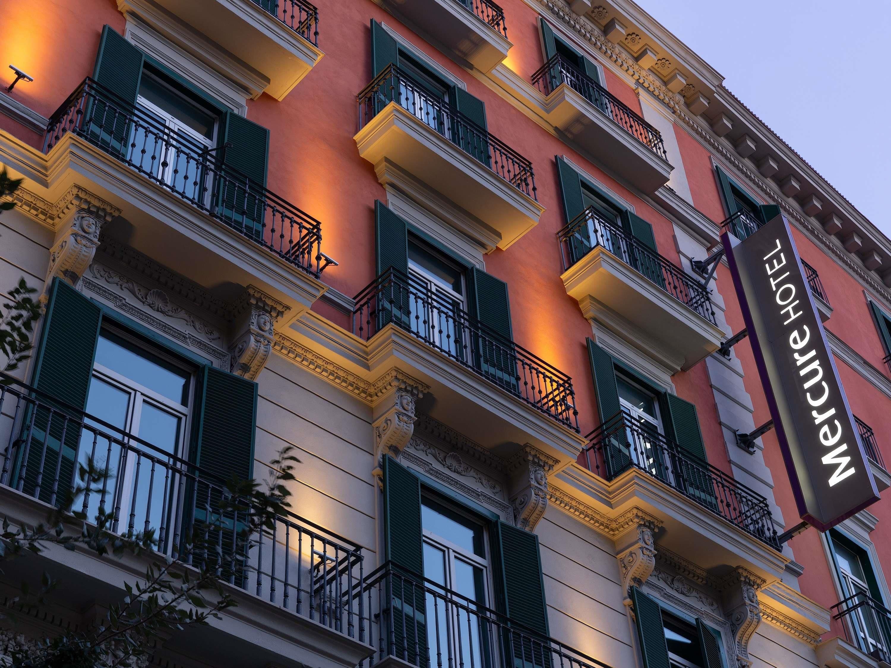 Un bâtiment d’hôtel doté de nombreux balcons, de volets verts et d’une enseigne indiquant qu’il s’agit de l’hôtel Mercure.