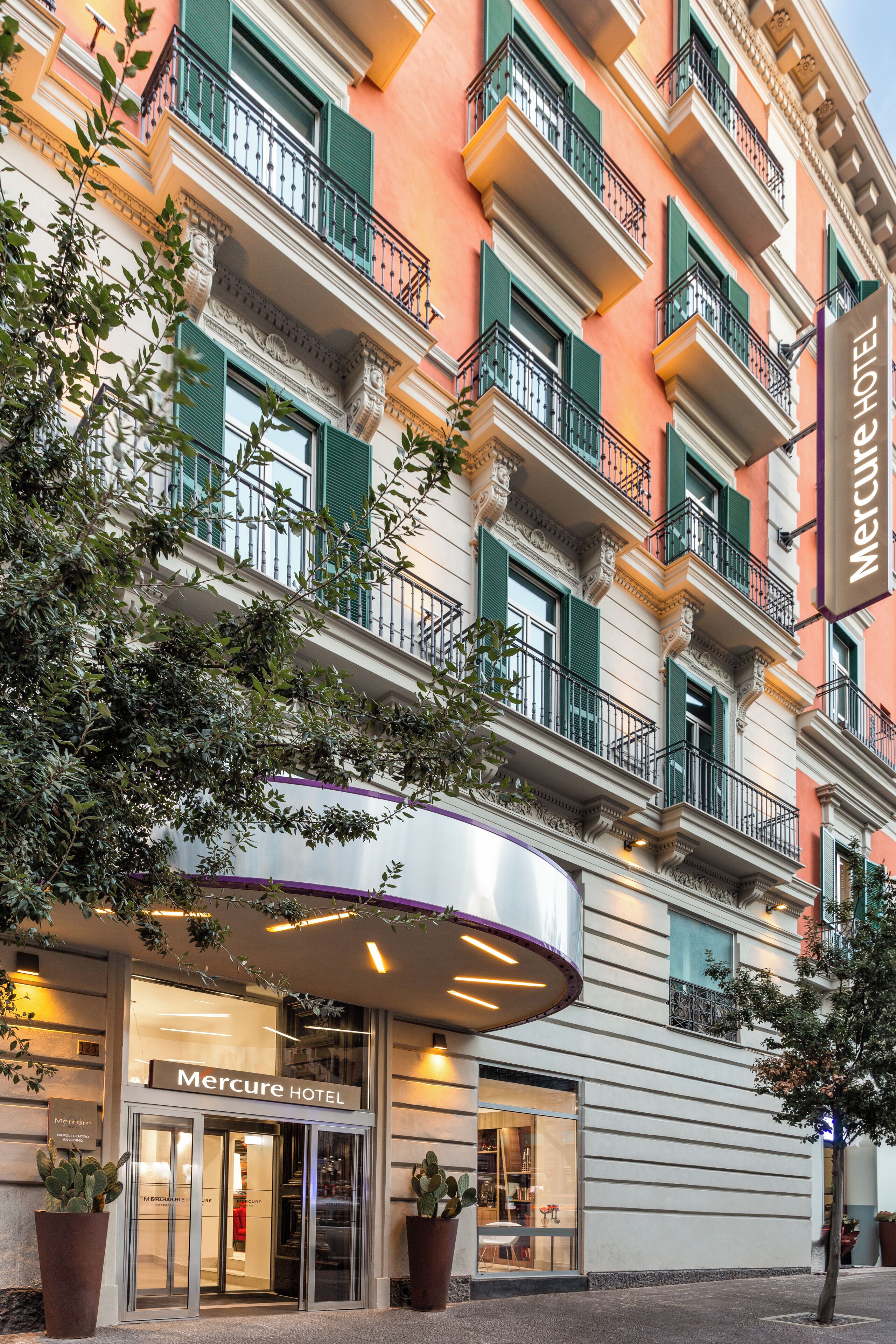 A hotel with a classic facade, green shutters, and a prominent entrance.