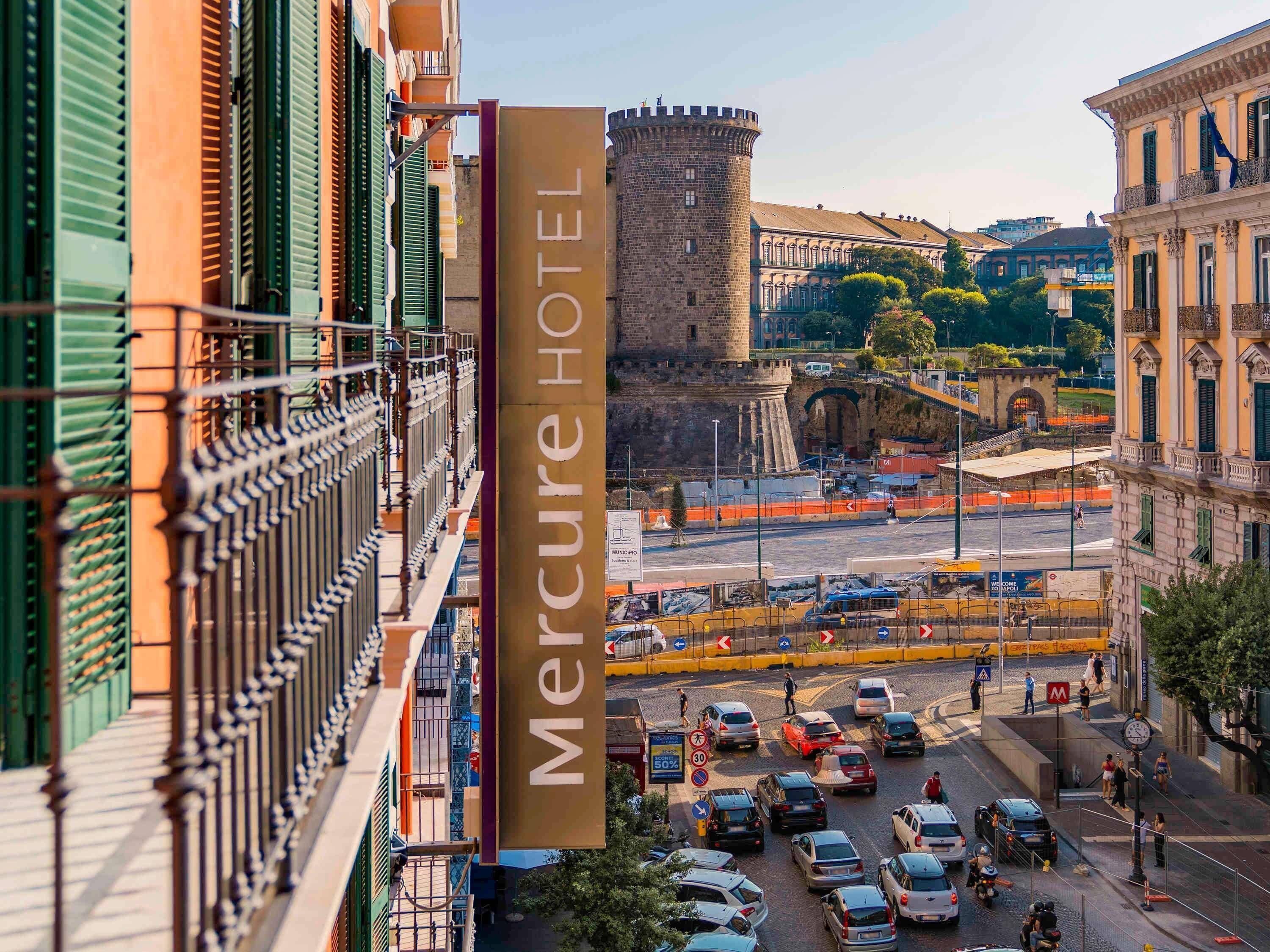 A Mercure Hotel sign with a view of a busy street and historic buildings in the background.