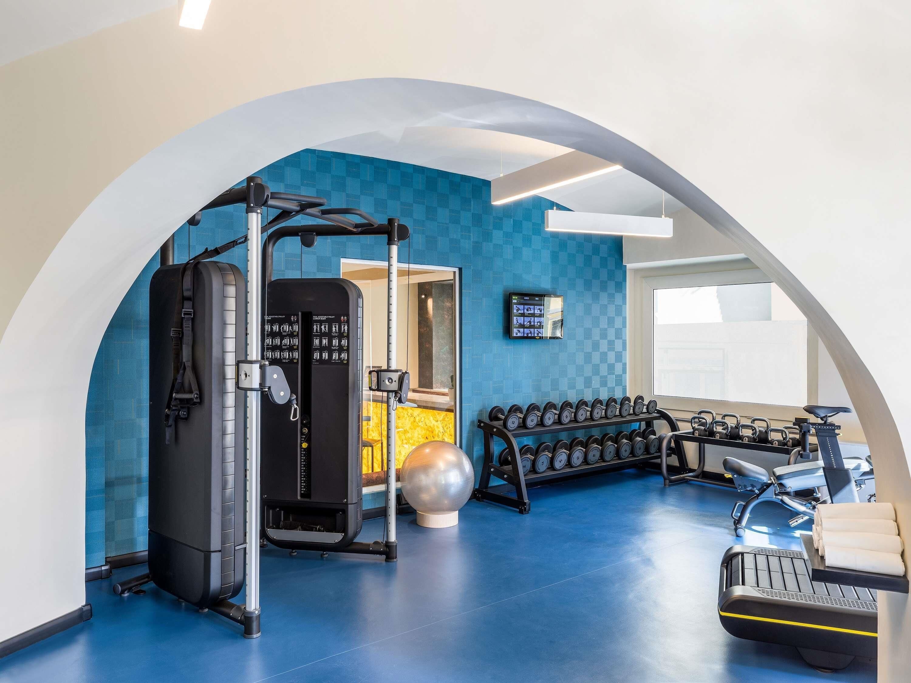 A gym with exercise equipment, a mirrored wall, and a blue floor.