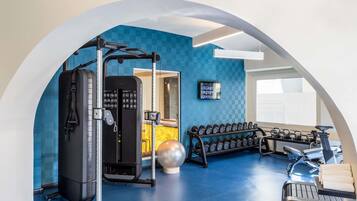 A gym with exercise equipment, a mirrored wall, and a blue floor.