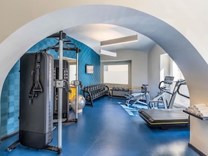 A gym with a squat rack, dumbbells, a treadmill, and a rowing machine. - Mercure Napoli Centro Angioino (Naples)