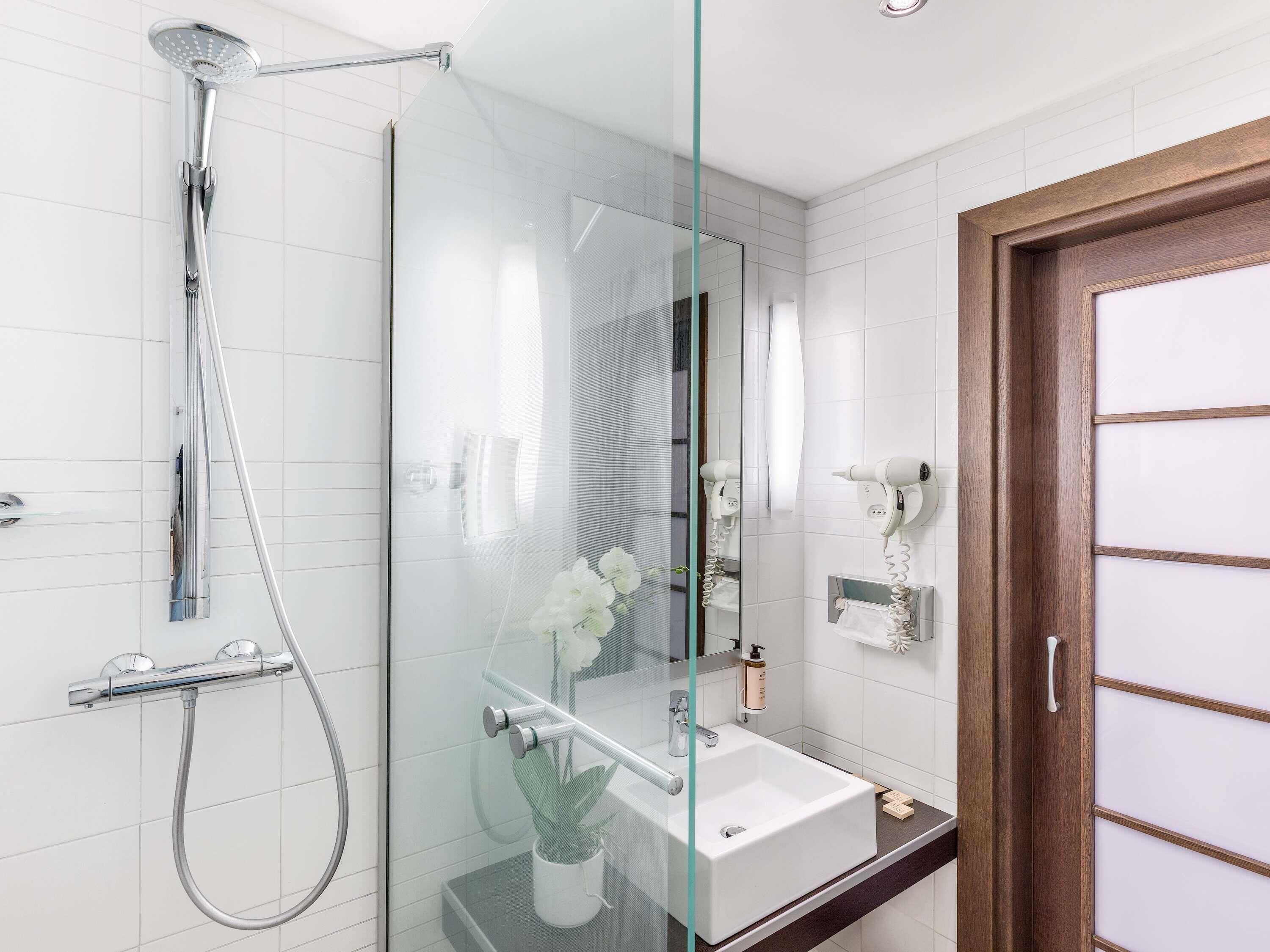 Une salle de bain moderne avec une douche à parois de verre, un lavabo blanc et une porte en bois.