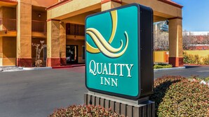 Segnale per Quality Inn, con vista chiara sull'ingresso dell'edificio e su un parcheggio.