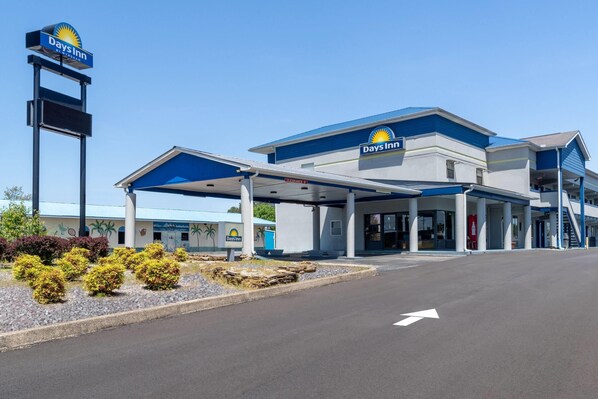 A Days Inn hotel with a clear road in front, a covered parking area, and a signboard. - Days Inn by Wyndham Greeneville (Greeneville)