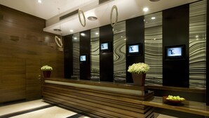 A reception area with a wooden reception desk, potted plants, and wall-mounted monitors. - Dan Boutique Jerusalem (Jerusalem)