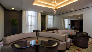 A modern hotel lobby with a curved sofa, round tables, and a ceiling light fixture. - Dan Boutique Jerusalem (Jerusalem)