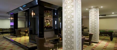 Un moderno vestíbulo de hotel con mesa de billar, zona de estar y paneles decorativos.