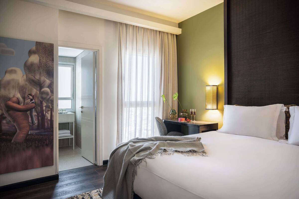 Une chambre d’hôtel avec un grand lit, un bureau avec une lampe et un tableau au mur.
