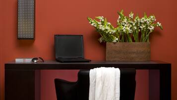 A desk with a laptop, a potted plant, and a chair with a white towel.