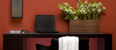A desk with a laptop, a potted plant, and a chair with a white towel.