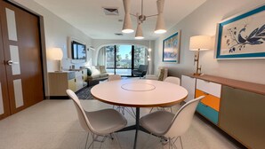 A modern hotel room with a round dining table, two chairs, a sofa, a TV, and a large window. - Howard Johnson by Wyndham Anaheim Hotel and Water Playground (Anaheim)