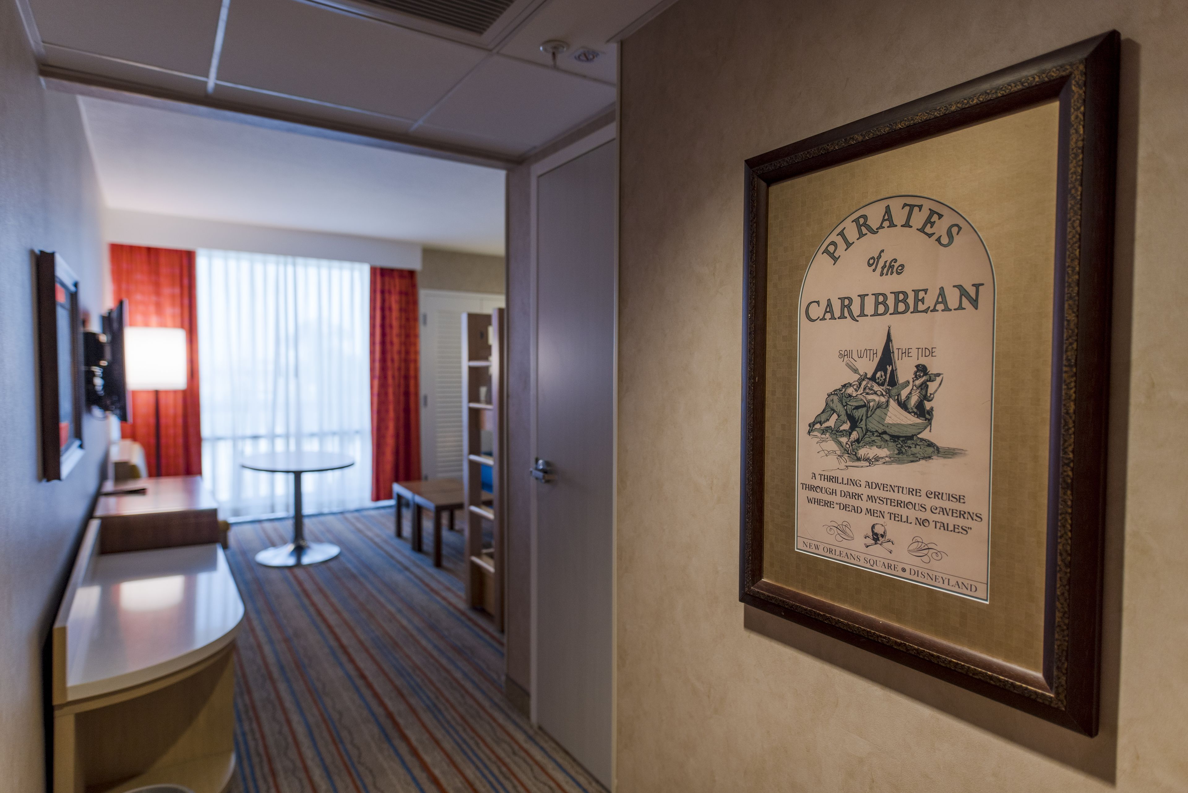 A framed poster of 'Pirates of the Caribbean' on a wall in a hotel hallway.