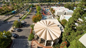 A large, uniquely designed building with a central dome structure, surrounded by parking areas and greenery. - Howard Johnson by Wyndham Anaheim Hotel and Water Playground (Anaheim)