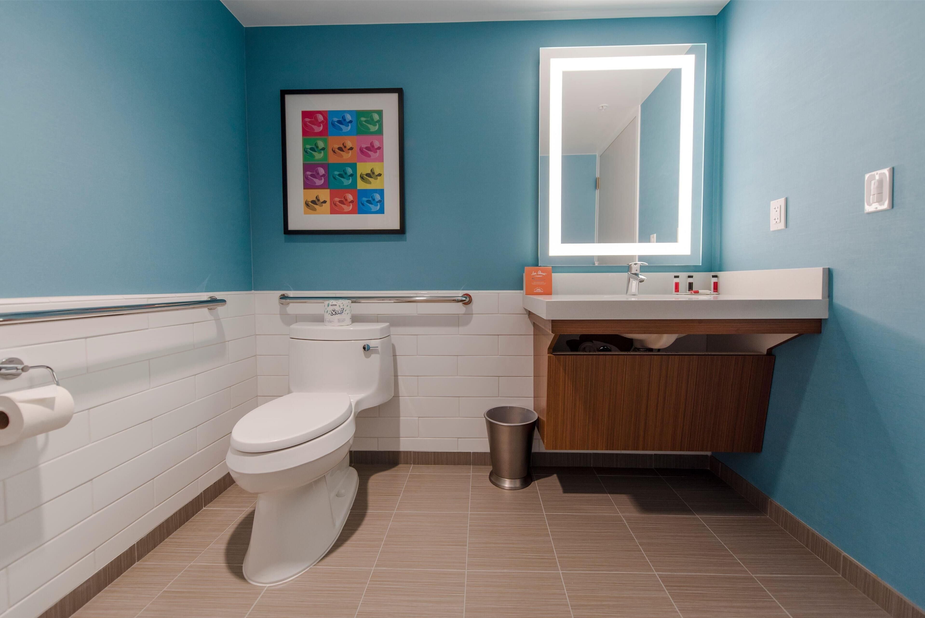 A modern bathroom with a toilet, sink, and mirror.