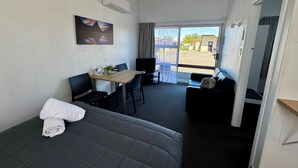 A room with a bed, a desk, a chair, a sofa, and a view of the outside. - Spanish Lady Motel (Napier)
