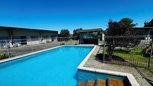 A rectangular swimming pool with a clear blue water surface, surrounded by a metal fence. - Spanish Lady Motel (Napier)