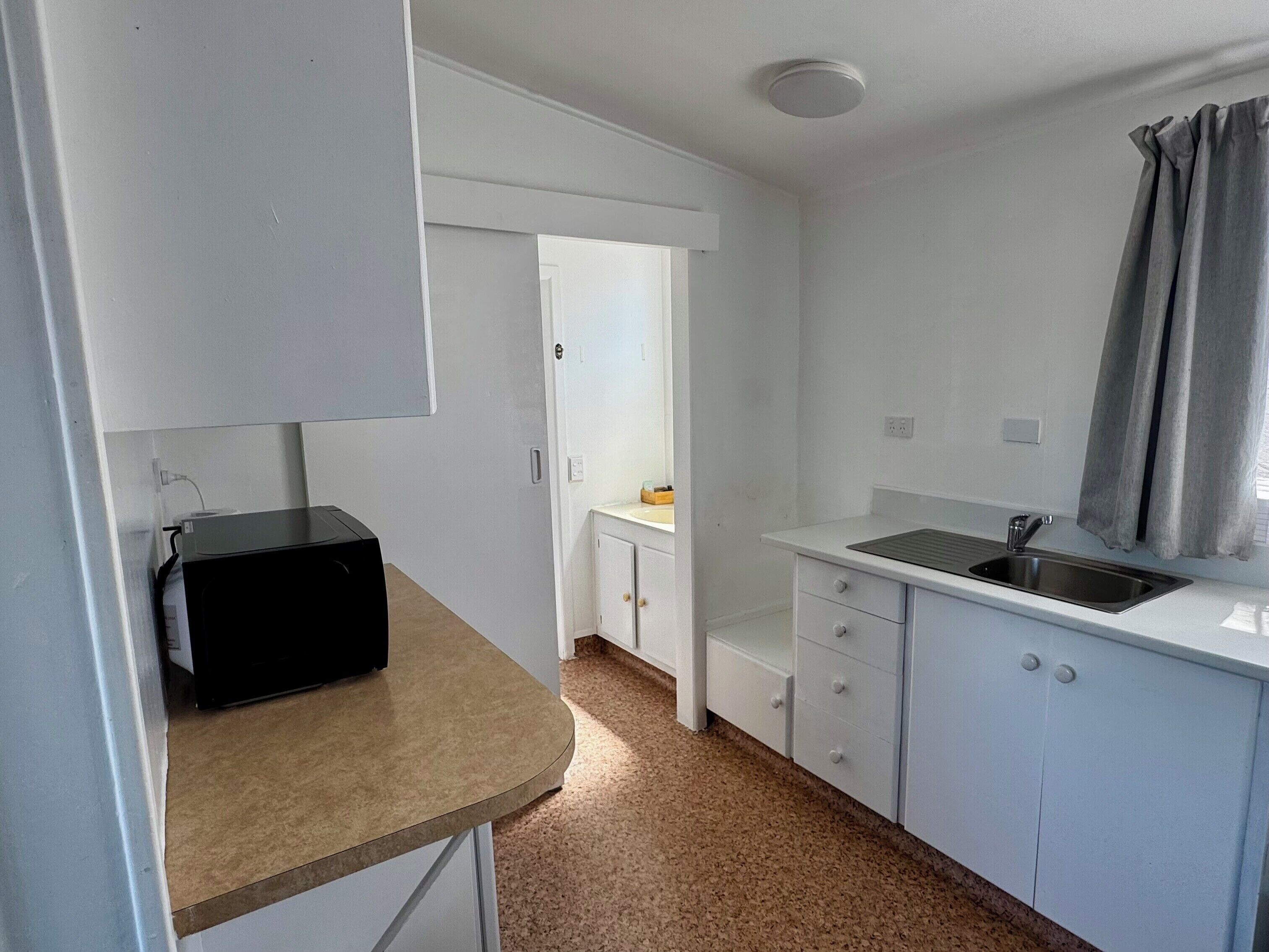 A small kitchenette with a microwave, a sink, and a cabinet.