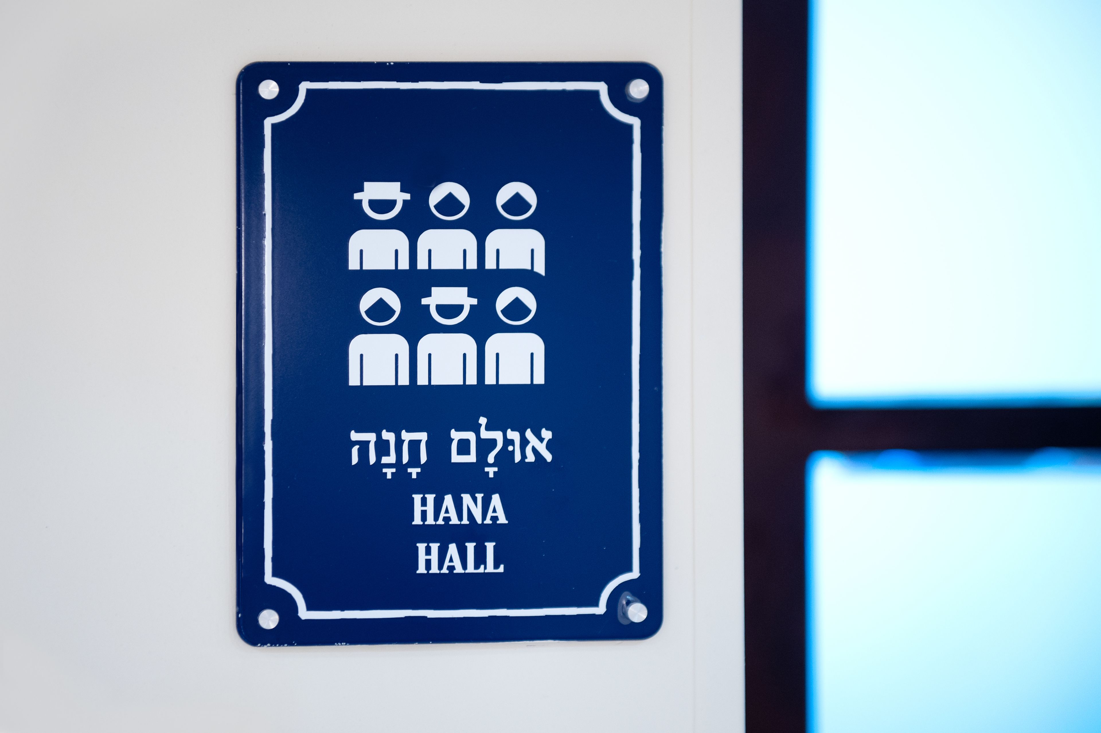 A sign for HANA HALL with symbols indicating facilities.