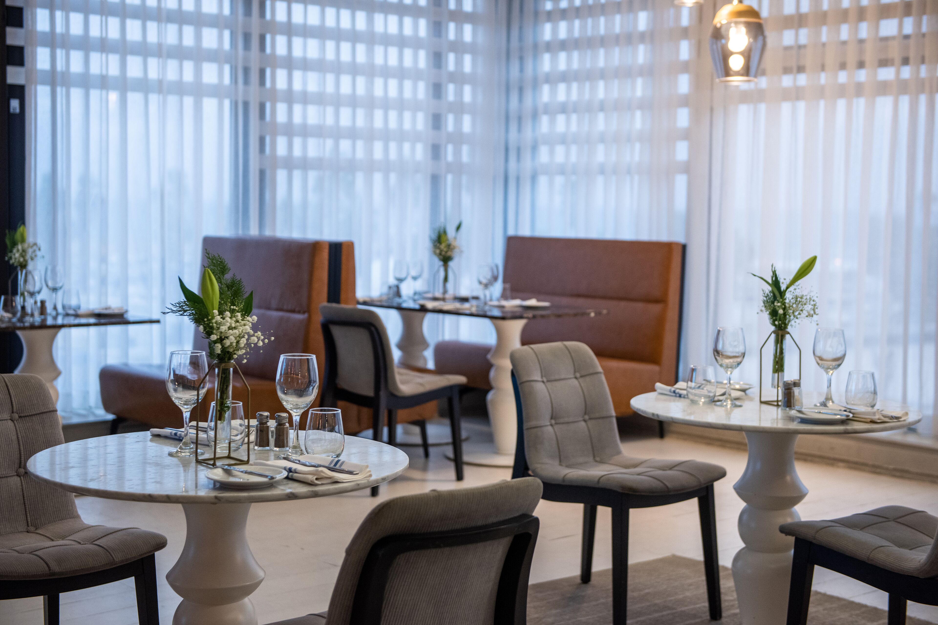 A modern dining area with round tables, cushioned chairs, and decorative centerpieces.
