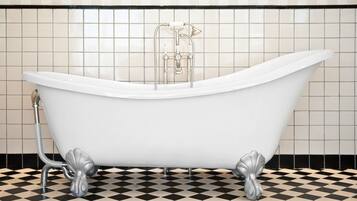A white freestanding bathtub with claw feet, a showerhead, and a handheld shower attachment, set against a tiled wall and floor.
