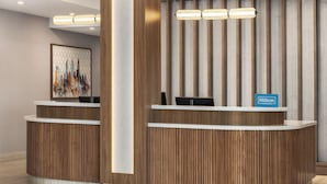 Een houten receptiebalie, een stadsgezicht kunstwerk aan de muur, en een Hilton Honors bord.