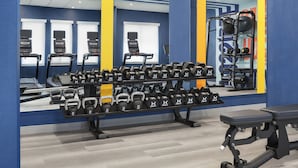 Een fitnessruimte met loopbanden, gewichtbanken en diverse gewichten.