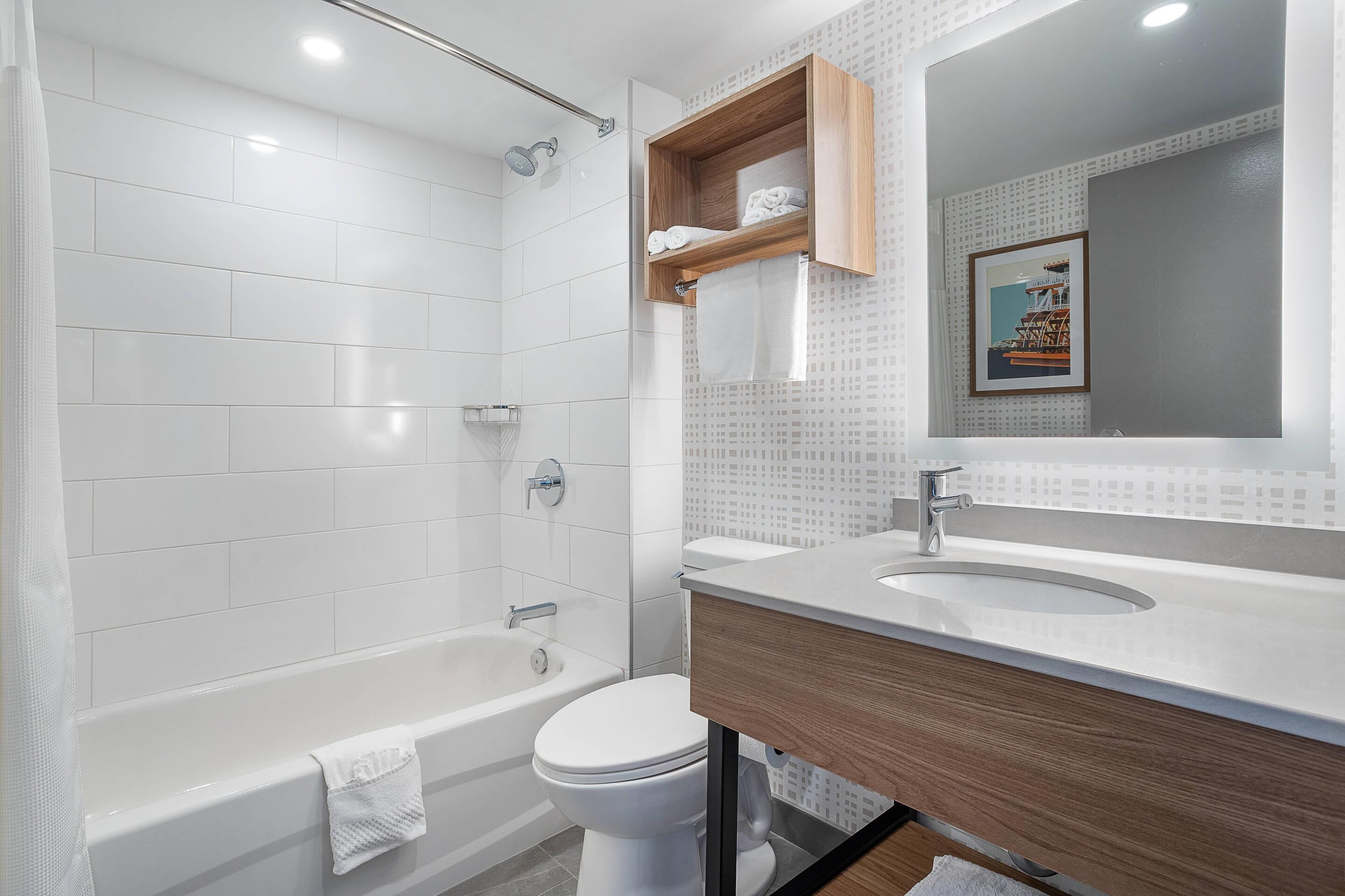 A modern bathroom with a bathtub, toilet, and vanity with a mirror.