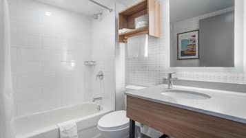 A modern bathroom with a bathtub, toilet, and vanity with a mirror.
