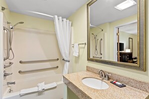 Bathroom features a bathtub, sink with granite countertop, and large mirror with gold frame.