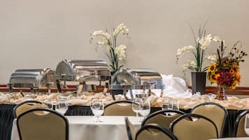 Een feesttafel gedekt met witte tafellinnen, zilveren buffetwagens en glazen.