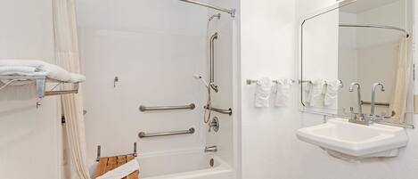 A bathroom with a bathtub, a sink, and a mirror.