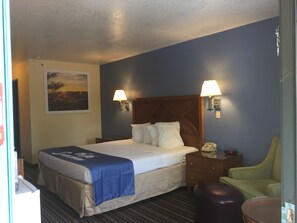 A hotel room with a bed, two bedside lamps, a nightstand, a chair, and a painting on the wall. - Days Inn by Wyndham Espanola (Espanola)