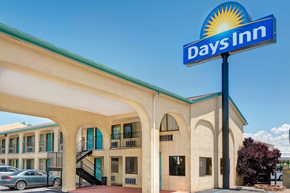 A Days Inn with a blue sign, a covered parking area, and a building with multiple windows and balconies. - Days Inn by Wyndham Espanola (Espanola)