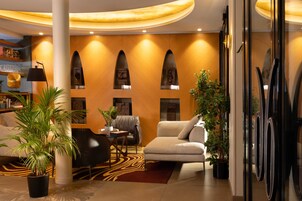 Un hall moderno con un sofá, sillones, una mesita de centro, una planta en maceta y una estantería.