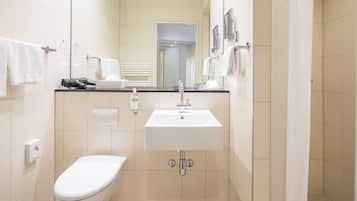 A modern bathroom with a white sink, toilet, and a mirror above the sink.