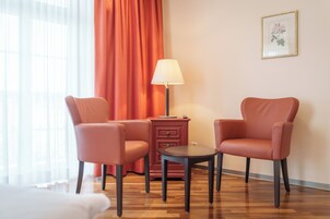 Una habitación con dos sillones de cuero, una mesita, una lámpara y una cortina roja.