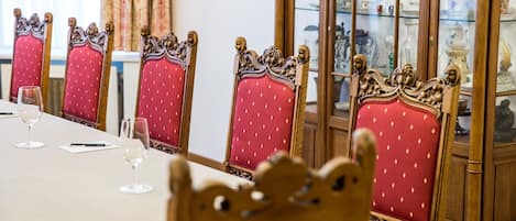 A dining table with chairs, a glass cabinet with decorative items, and a window with curtains.