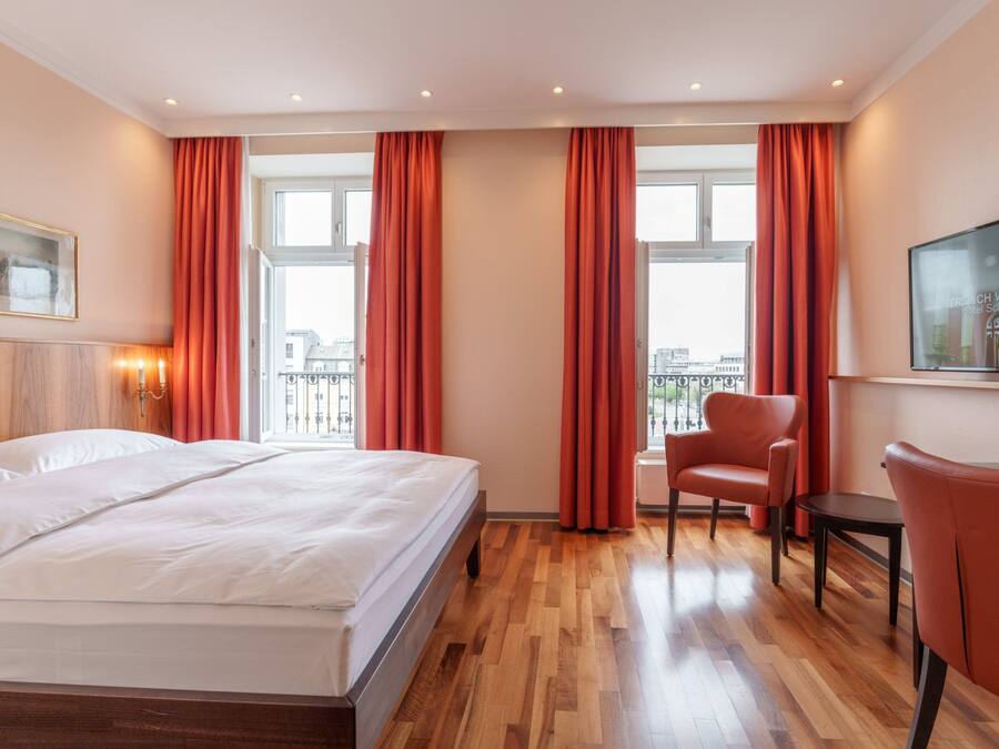 Una habitación de hotel con una cama, una silla, una mesita y un cuadro en la pared.