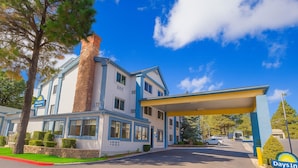 A motel with a gas station, a brick chimney, and a clear blue sky.
