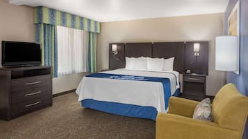 A hotel room with a bed, a TV, a desk, and a chair.